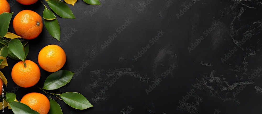 Poster top view of a flat lay fruit composition featuring an orange or tangerine with leaves placed on a bl