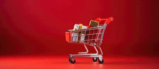 Christmas themed shopping cart toy on a red background Copy space image with discounts and sale