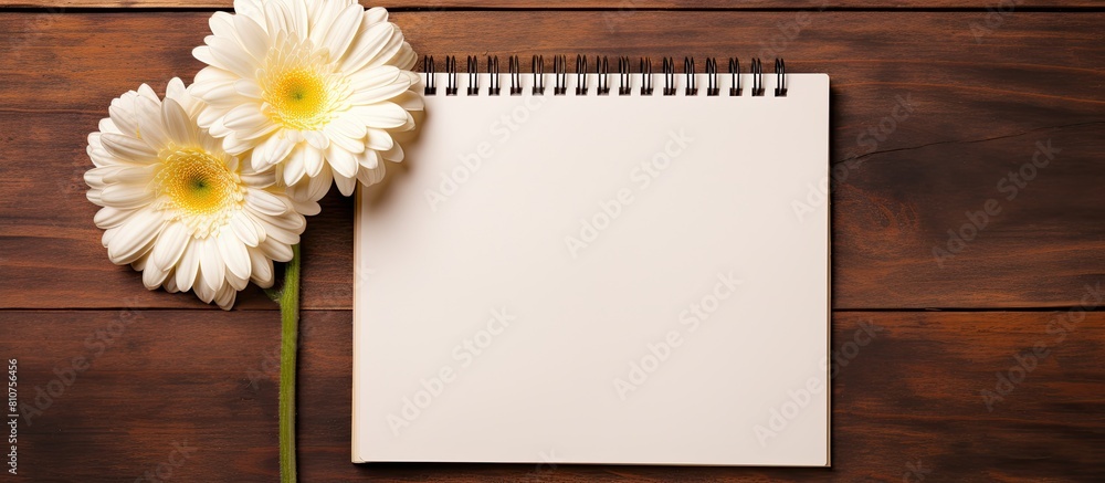 Poster top view copy space image of three gerbera flowers and a blank paged notebook resting on a wooden ta