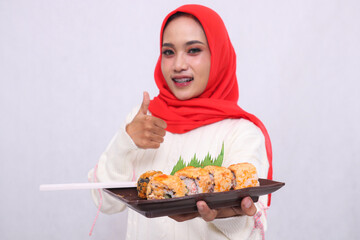 a plate containing sushi (Japanese food) held by a beautiful Asian woman while smiling with a...