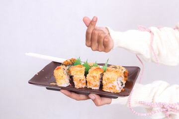 a plate (closeup and front angle) containing a sushi dish (Japanese food) a gesture of love (saranghaeyo) held by a woman's hand for culinary, food and lifestyle content