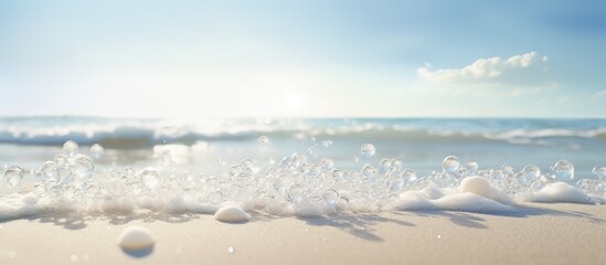 A diagonal line of white sea foam dotted with small bubbles glistens in the bright sunlight as the wet beach sand lies in the foreground creating a copy space image