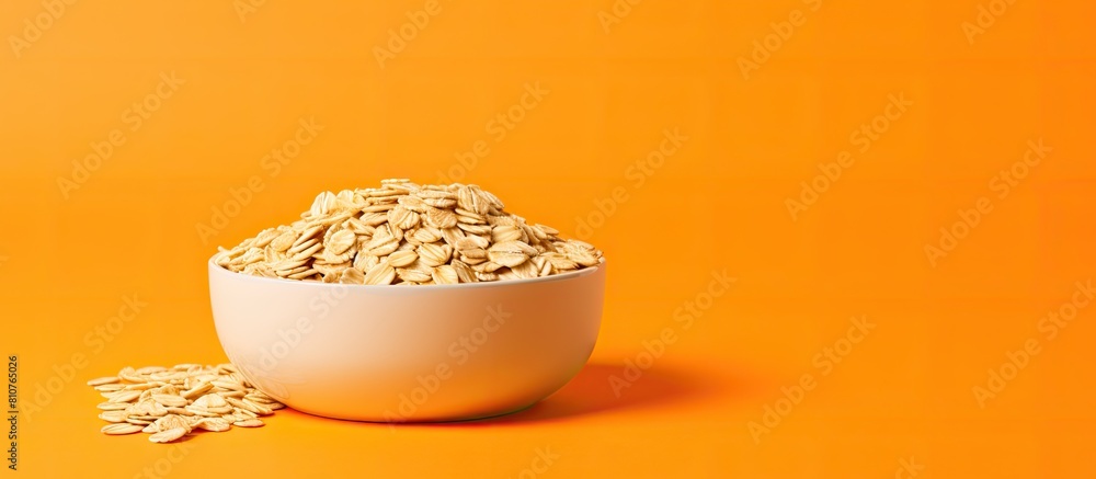 Poster copy space image of a bowl filled with uncooked oatmeal flakes placed on a vibrant orange background