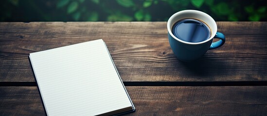 There is a copy space image of a school notebook placed on a table next to a cup of coffee