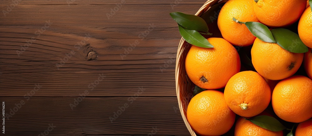Poster The copy space image shows a top view of a basket filled with freshly picked oranges resting on a wooden table