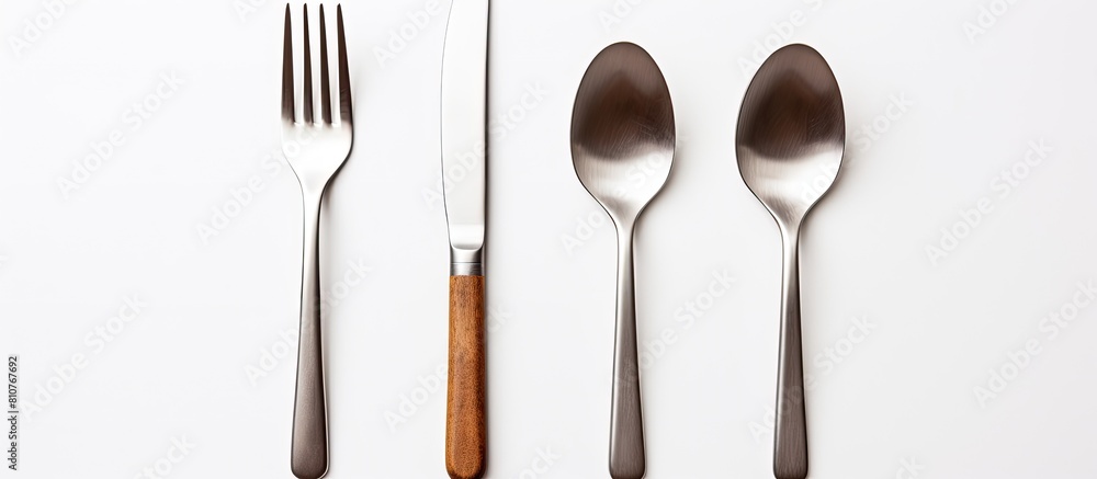 Poster A silver fork spoon and knife are seen on a white background arranged in a flat lay with a top down view There is empty space available for adding text or other images. Creative banner