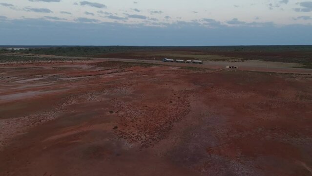 Drone clip showing truck with multiple carriages driving along straight road through Australian outback