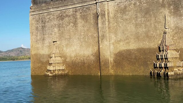 The ruins of the ancient Buddhist temple Wat Saam Prasob, half-submerged in the waters of Lake Khao Laem in Sangkhlaburi, Thailand.