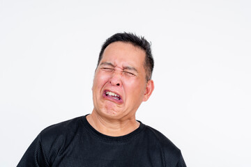 A middle aged Asian man grimaces with a yuck facial expression after tasting something bitter,...