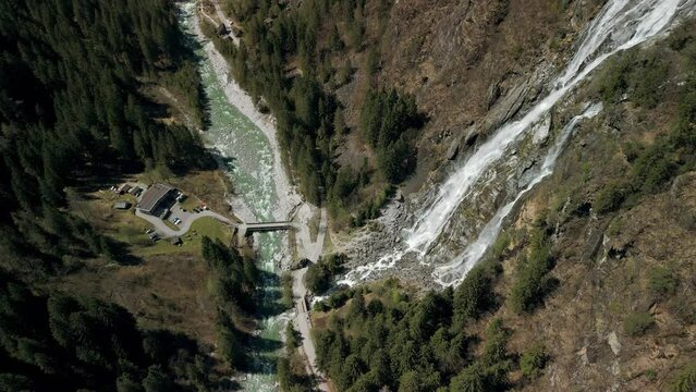 Restaurant in front of Nardis Waterfall and Sarca River crossing Val di Genova, Trentino in Italy. Aerial top-down orbiting. 