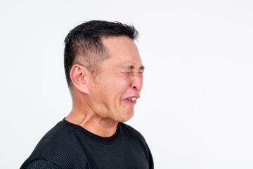 Obraz premium Side view of a middle-aged Asian man shows a puckered expression reacting to sour taste, isolated on a white background.
