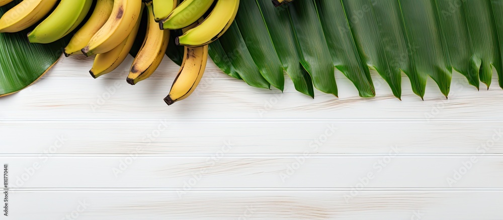 Poster a tropical fruit the banana is placed on a white wooden table alongside vibrant green leaves the top