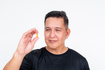 A middle-aged Asian man holds a multivitamin capsule, displaying it prominently against a white background, focusing on health and wellness.