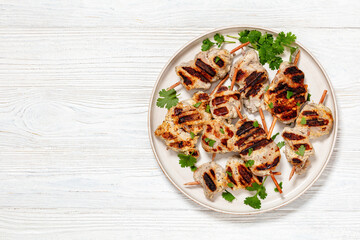 grilled mini pork skewers on a plate, top view