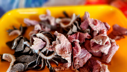 Macro close-up of raw, freshly sliced beef tripe arranged on a bright orange tray
