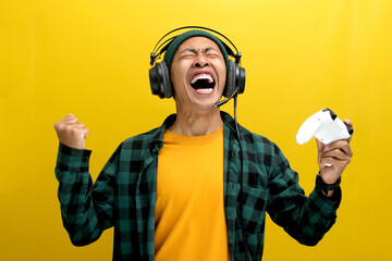 An enthusiastic Asian gamer, adorned in a beanie hat, casual shirt, and headphones, celebrates...