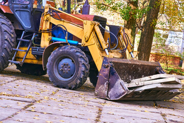 Excavator bulldozer loads old concrete slabs on road repair