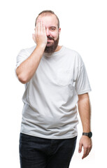 Young caucasian hipster man wearing casual t-shirt over isolated background covering one eye with hand with confident smile on face and surprise emotion.