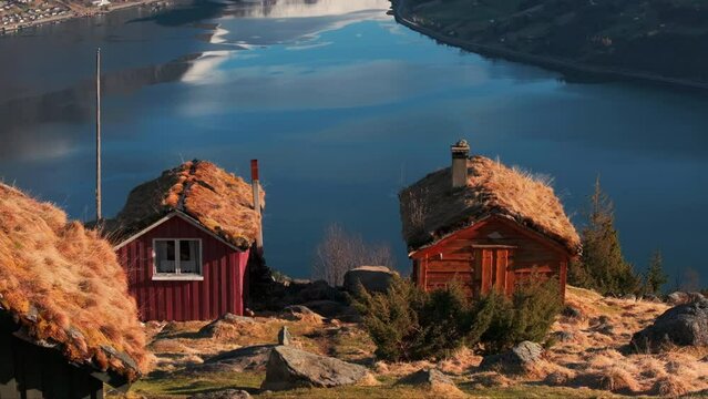 Rakssetra cabins in sunset glow overlooking idyllic Norway valley fjord; drone