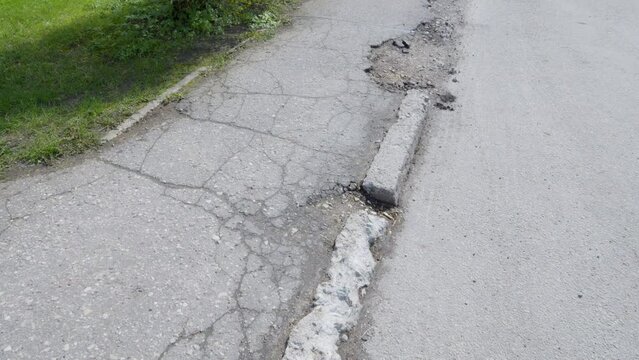 Old cracked and fragmented asphalt in city street and sidewalk