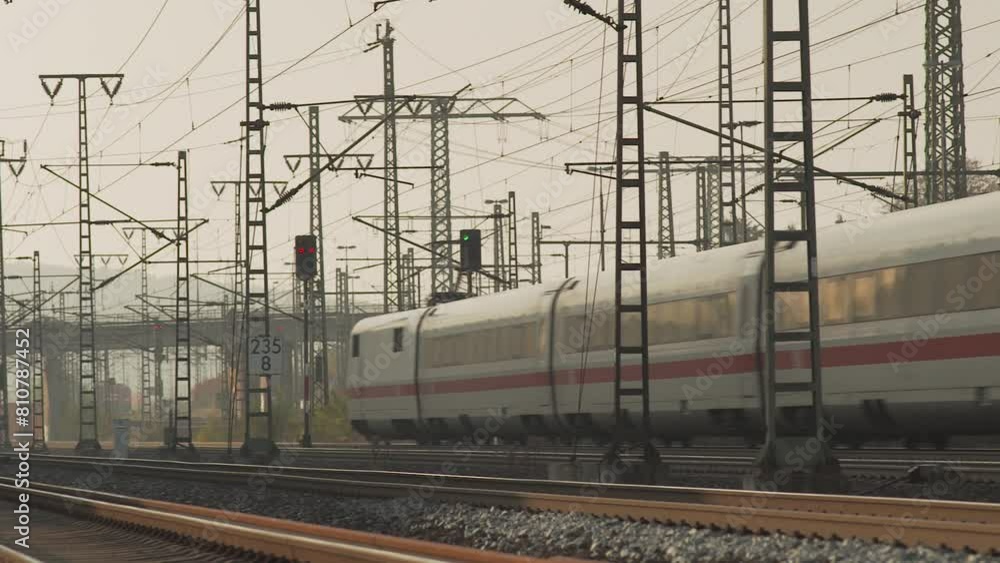 Poster high-speed train speeding through a station with a complex network of electric lines