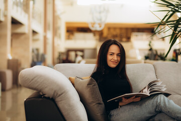 a woman sitting on the couch looking at a furniture catalog in a furniture store