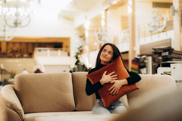 Pretty, young woman choosing the right furniture for her apartment in a modern home furnishings store