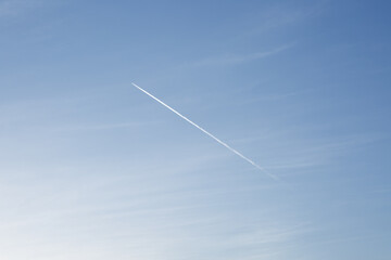 Tiny flying plane in blue sky with trail