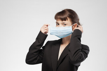 Young businesswoman adjusting medical face mask in a neutral background