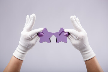 Violet star eyeglasses in hands with white gloves