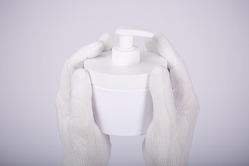 White jar with cream in hands in white gloves