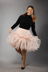 Captured in motion, this joyful woman spins in her delicate pink skirt and fashionable black top, creating a lively and cheerful look.