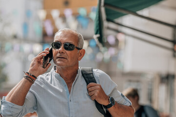 mature man with backpack and phone on the street