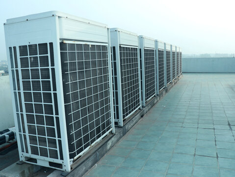 Rows of rooftop HVACs on the rooftop of an office tower. VRF air conditioner for commercial buildings- Row Of Air Conditioning Units On A Rooftop.