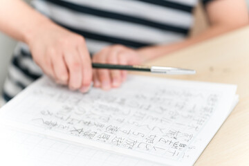 漢字練習で消しゴムで字を消す小学生低学年の子供の手元
