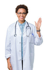 Fototapeta premium Young african american doctor woman wearing medical coat over isolated background Waiving saying hello happy and smiling, friendly welcome gesture