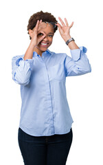 Young beautiful african american business woman over isolated background doing ok gesture with hand smiling, eye looking through fingers with happy face.