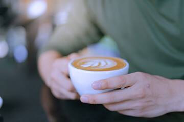 Young man's hand holding hot coffee