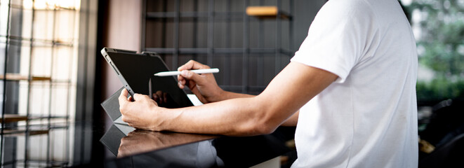 Young man holds a pen and writes on a tablet