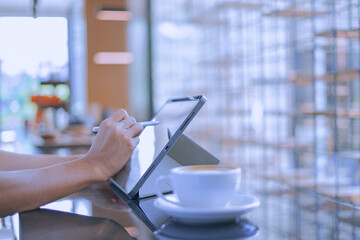 Young man holds a pen and writes on a tablet