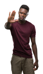 Fototapeta premium Young african american man with open hand doing stop sign with serious and confident expression, defense gesture
