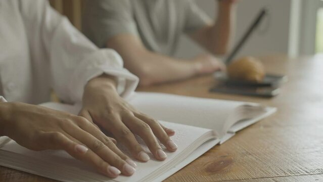 Close up view of woman hands touching a book. A blind woman reads a book in Braille. A blind or visually impaired person reads a book written in Braille. Reading a book in Braille