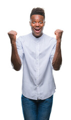 Fototapeta premium Young african american man over isolated background celebrating surprised and amazed for success with arms raised and open eyes. Winner concept.