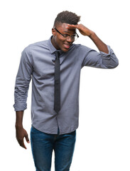 Fototapeta premium Young african american business man over isolated background very happy and smiling looking far away with hand over head. Searching concept.