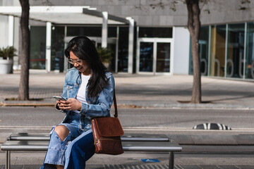 Young woman waiting for a train. Woman holding mobile in a train station. Commuting to work. Public transport concept.