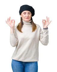 Middle age mature woman wearing winter sweater and beret over isolated background relax and smiling with eyes closed doing meditation gesture with fingers. Yoga concept.