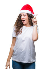 Young brunette girl wearing christmas hat over isolated background pointing finger up with successful idea. Exited and happy. Number one.