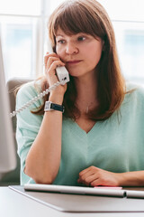 An attentive professional woman engaging in a conversation on an office phone, showcasing modern workplace communication.