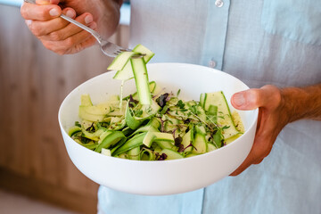 Vibrant zucchini ribbon salad, a healthy and fresh dish in the hands of a man with a taste for...