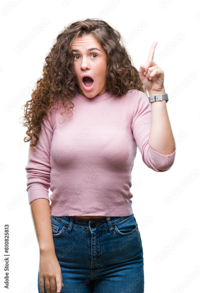 Sticker Beautiful brunette curly hair young girl wearing pink sweater over isolated background pointing finger up with successful idea. Exited and happy. Number one.